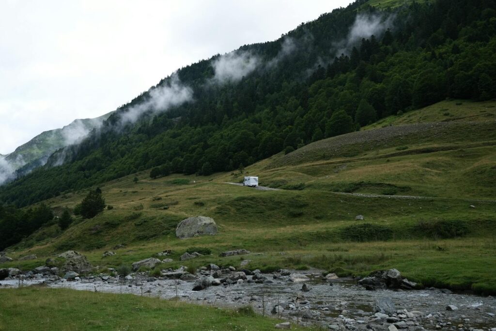 Peaceful mountain landscape with stream, fog, and lush greenery offering serene tranquility.